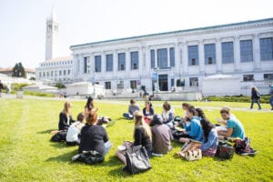 a group of students and an instructor sits in the grass on the Berkeley campus