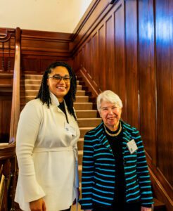 Assistant Professor Samantha Lewis and Chancellor Carol Christ standing in front of a staircase in University House.
